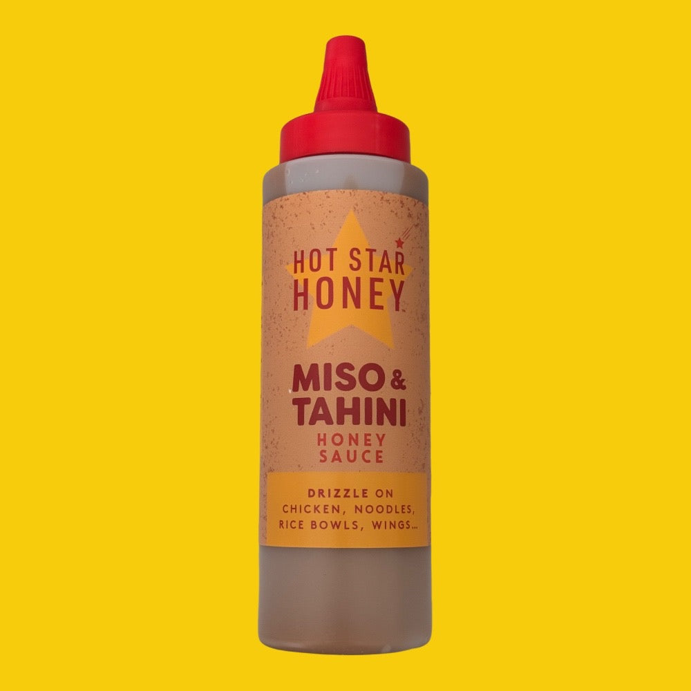 A squeeze bottle of Hot Star Honey Miso & Tahini Honey Sauce centered against a solid bright yellow background.