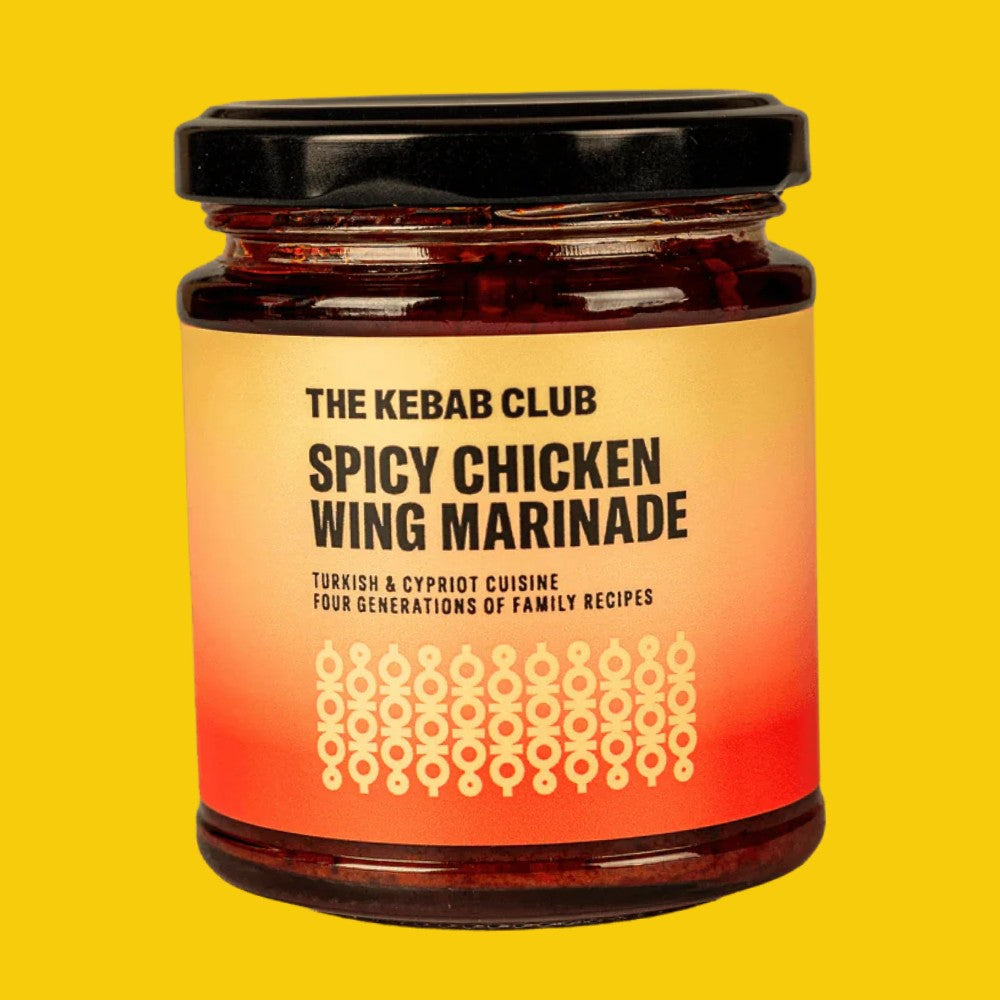 A glass jar of The Kebab Club Spicy Chicken Wing Marinade with a black lid and a warm orange-to-yellow gradient label, set against a solid yellow background.